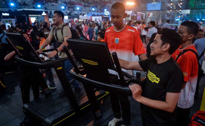 参观者正在体验展出的跑步机等健身器材。