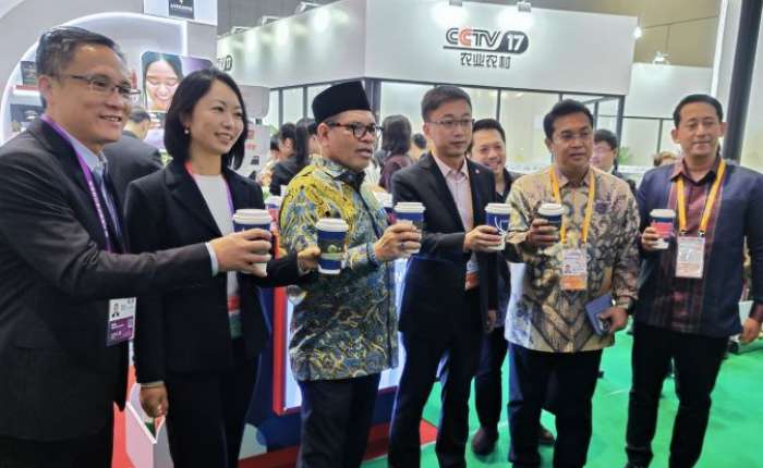 印尼驻华大使周浩黎（佩戴印尼传统帽）在上海举行的第八届进博会 印尼展馆内，手持来自“瑞幸咖啡”的饮品。