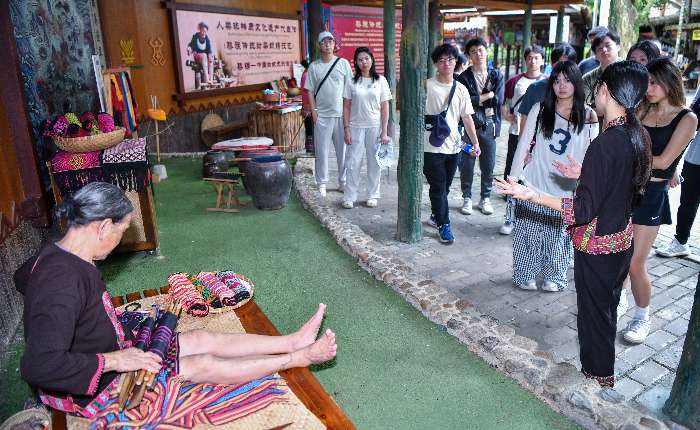 7月19日，在保亭黎族苗族自治县的海南槟榔谷黎苗文化旅游区，黎族阿婆展示黎族传统纺染织绣技艺吸引游客观看。 中新社记者 骆云飞 摄