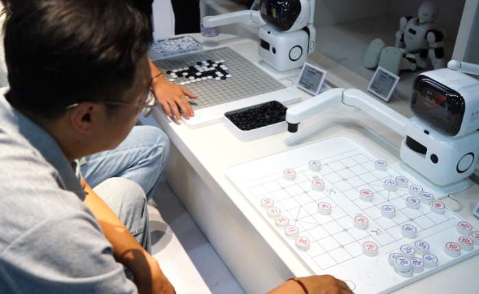 8月6日，北京，参观者和全球首家具身智能机器人4S店内展示的机器人下棋。张天润 摄