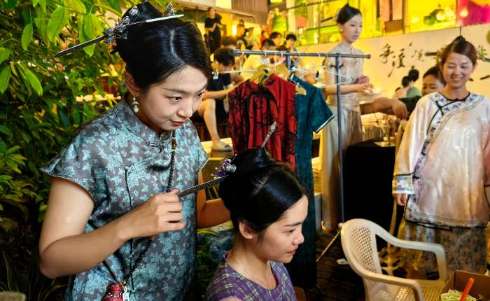 8月23日晚，在福州烟台山历史风貌区的“三条簪”体验现场，工作人员正在给一位女孩边梳妆边讲解头饰背后的文化寓意。 中新社记者 闫旭 摄