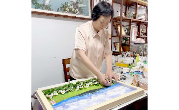 图为近期郭美瑜在工作室内创作一幅水仙花主题的棉花画。 （受访者供图）