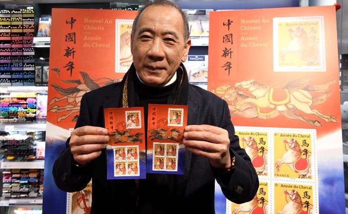 图为法国生肖邮票设计师、法籍华裔画家陈江洪在仪式现场向大家展示邮票。(中新社)