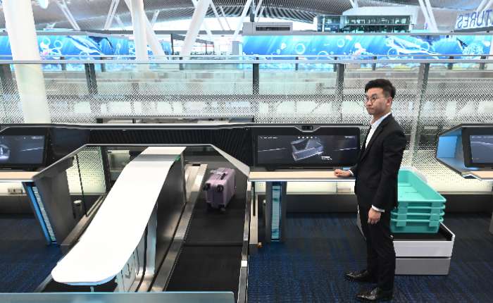 图为现场人员示范自助托运行李。