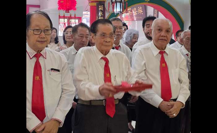 3.	陈本洋（中）敬献花果。